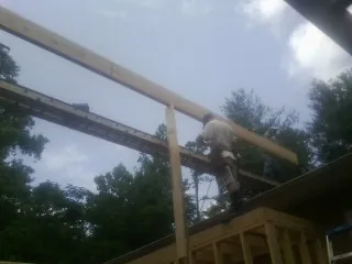 Carpenter setting a ridge beam over a new addition frame — Ice Dam Removal by Roofing Brothers in Bouton