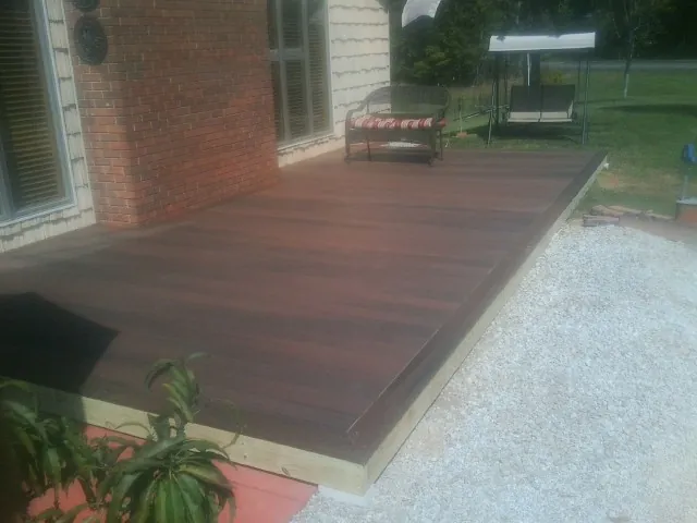 Freshly stained wood deck built against a brick home in Bouton