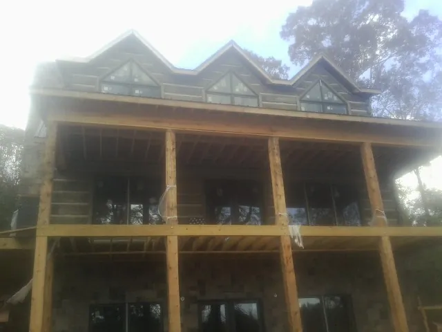 Dormers and porch framing on a large log home under construction — Roof Coating work by our crew in Bouton