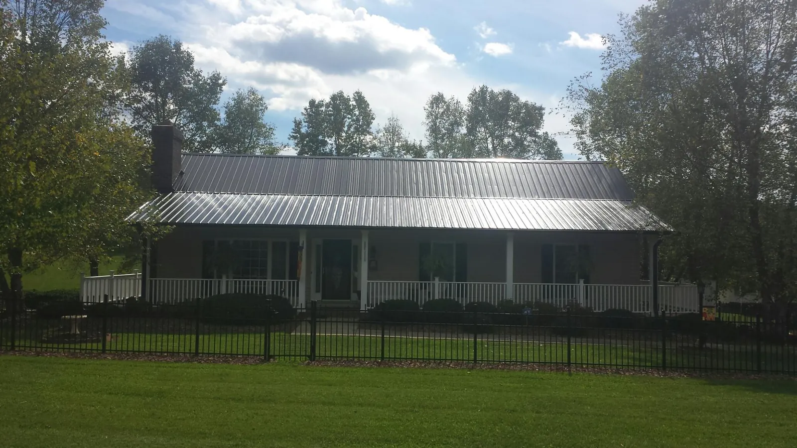 Gray metal roof on a brick ranch with a full width front porch — Gutter Guard Installation work by our crew in Bouton