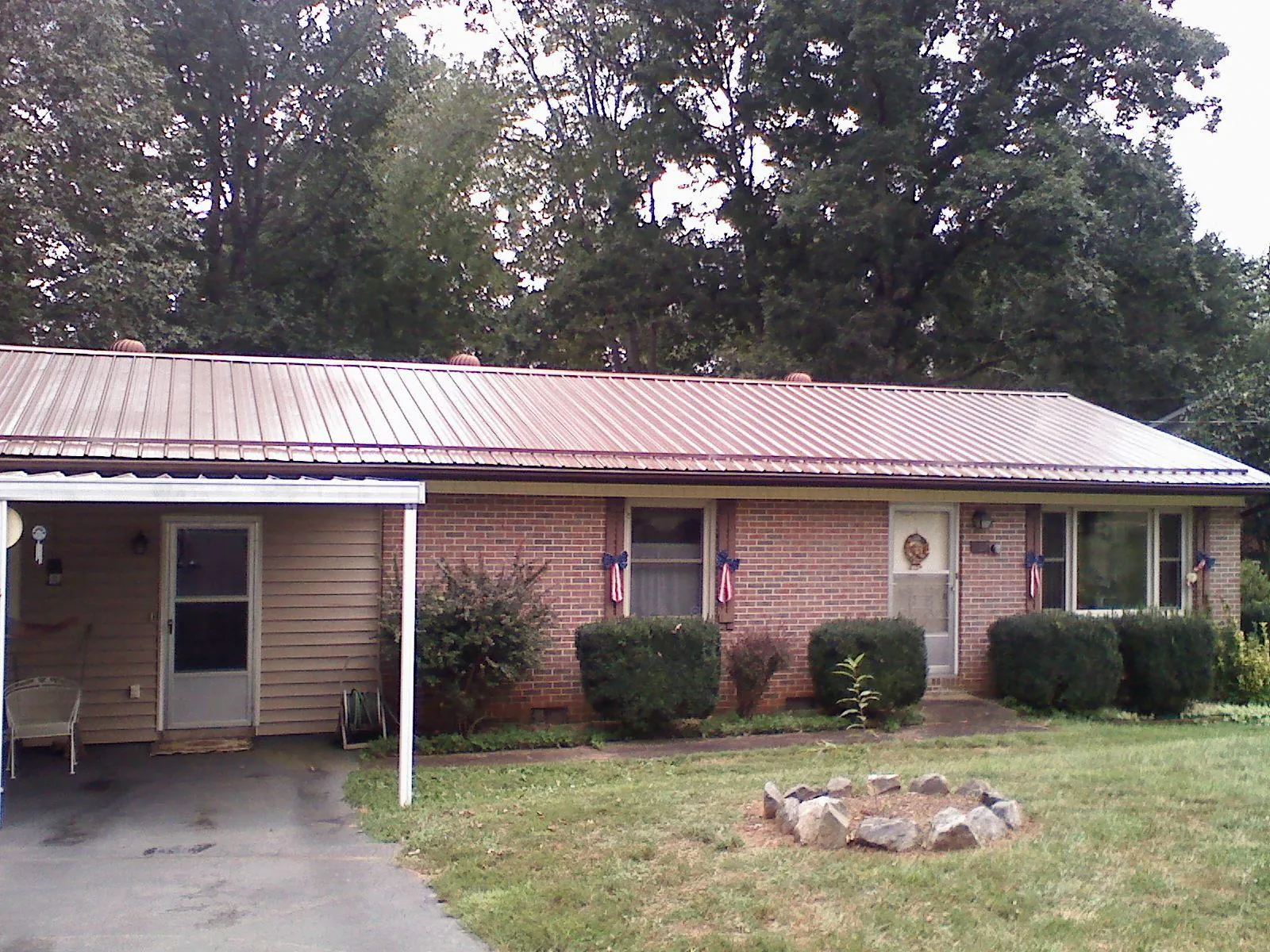 Bronze metal roof and carport on a brick ranch home — Roof Repair work by our crew in Bouton