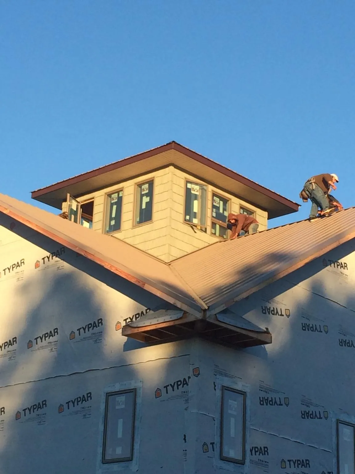 Roofers working around a rooftop cupola on a new metal roof at sunset — Roof Waterproofing in Bouton by Roofing Brothers